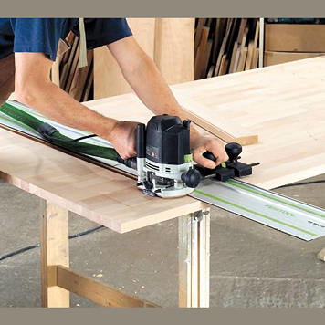 Person using a Festool 576213 OF 1400 EQ-F-Plus router with guide rail on wooden board for precision woodworking