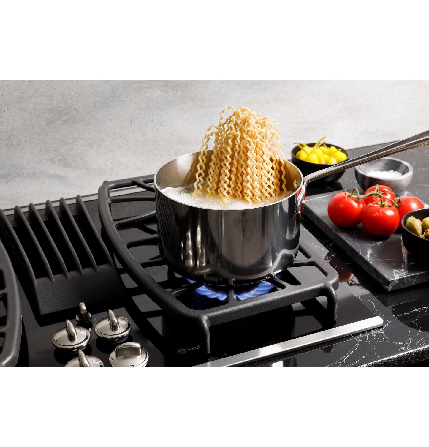 Boiling pasta in a stainless steel pot on a modern built-in gas downdraft cooktop in a kitchen setting