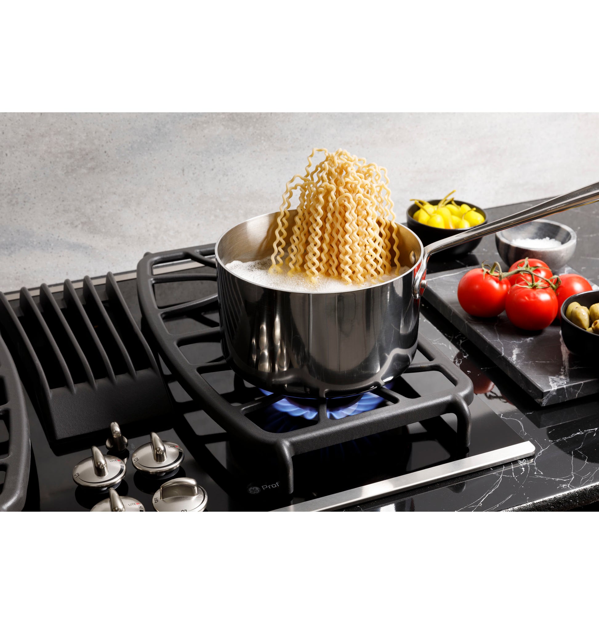 Boiling pasta in a stainless steel pot on a modern built-in gas downdraft cooktop in a kitchen setting