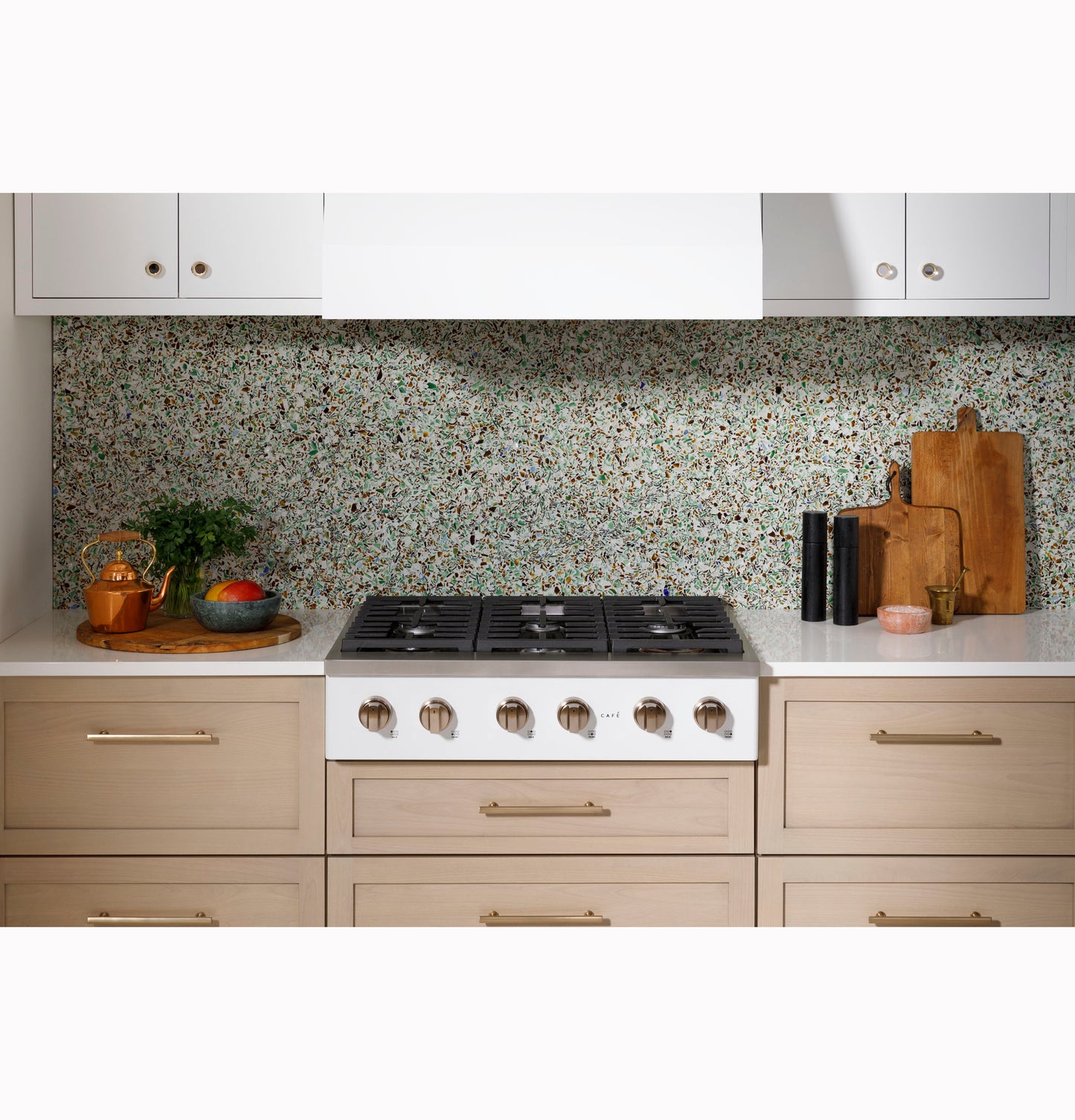 Modern kitchen setup featuring a six-burner gas rangetop with natural wood cabinetry and terrazzo backsplash for home improvement.