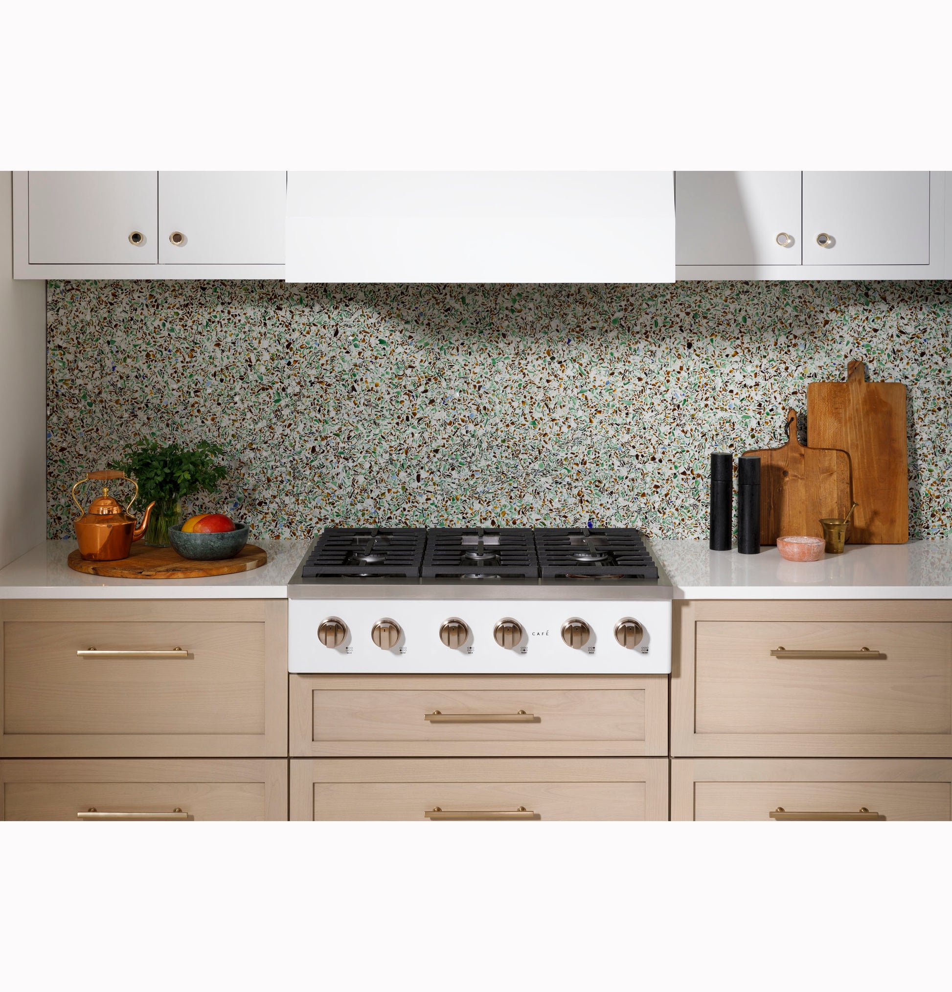 Modern kitchen setup featuring a six-burner gas rangetop with natural wood cabinetry and terrazzo backsplash for home improvement.
