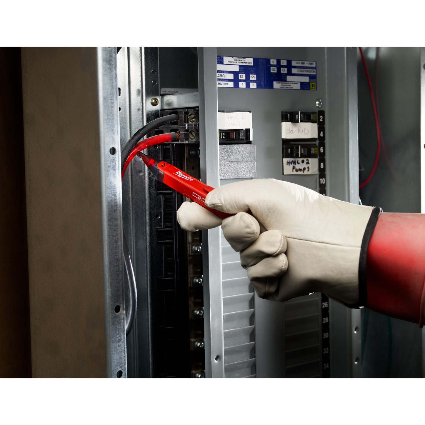 Handheld red voltage detector testing live wires inside electrical panel with protective glove for tools and home improvement use