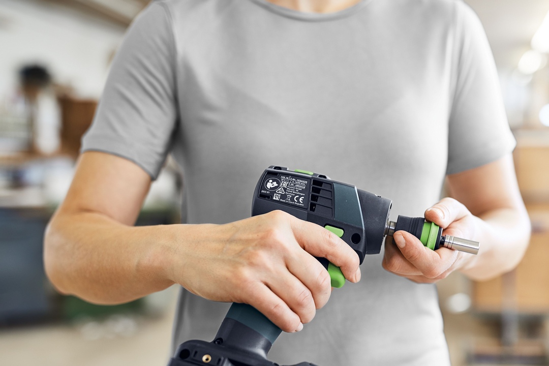 Person attaching drill accessory to Festool cordless drill in a workshop setting for home improvement tasks