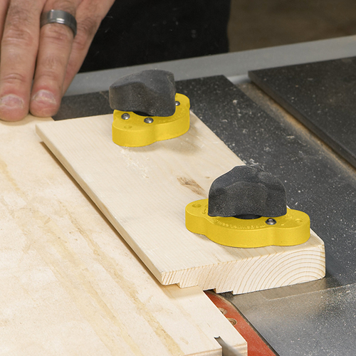 Yellow magnetic hold-down clamps securing wood piece on table saw for woodworking and power tool accessories collections