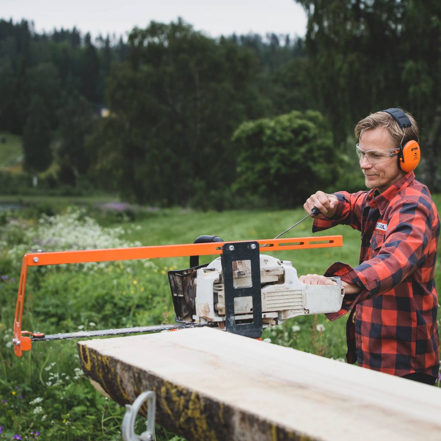 Orange top steering bar attached to chainsaw for precise log cutting in outdoor home improvement tasks