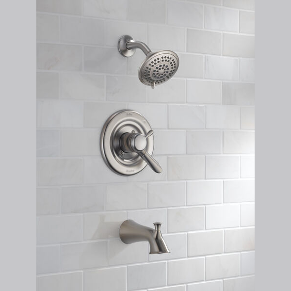 Stainless steel tub and shower trim with single handle control and adjustable showerhead in a tiled bathroom setting
