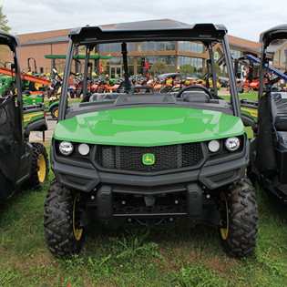 Front view of a green John Deere utility vehicle equipped with rugged predator terrain tires on grass