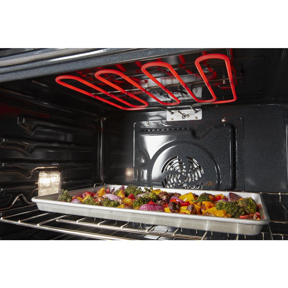 Tray of colorful vegetables roasting under glowing heating element inside stainless steel wall oven cavity