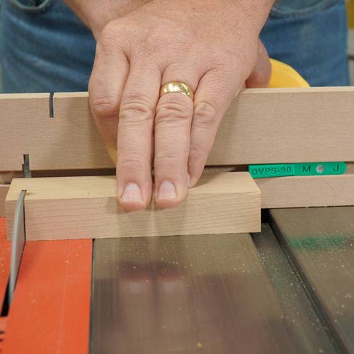 Hand pressing wooden block against a microjig MATCHFIT stop on a table saw for precise cuts in woodworking tasks
