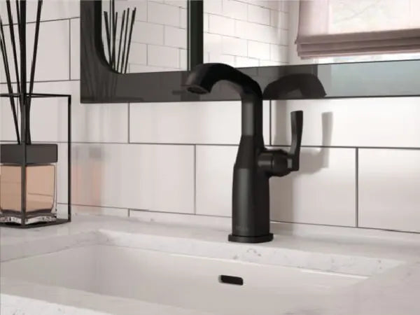 Modern matte black kitchen faucet with a single lever handle mounted on a white quartz countertop against a white tiled backsplash.
