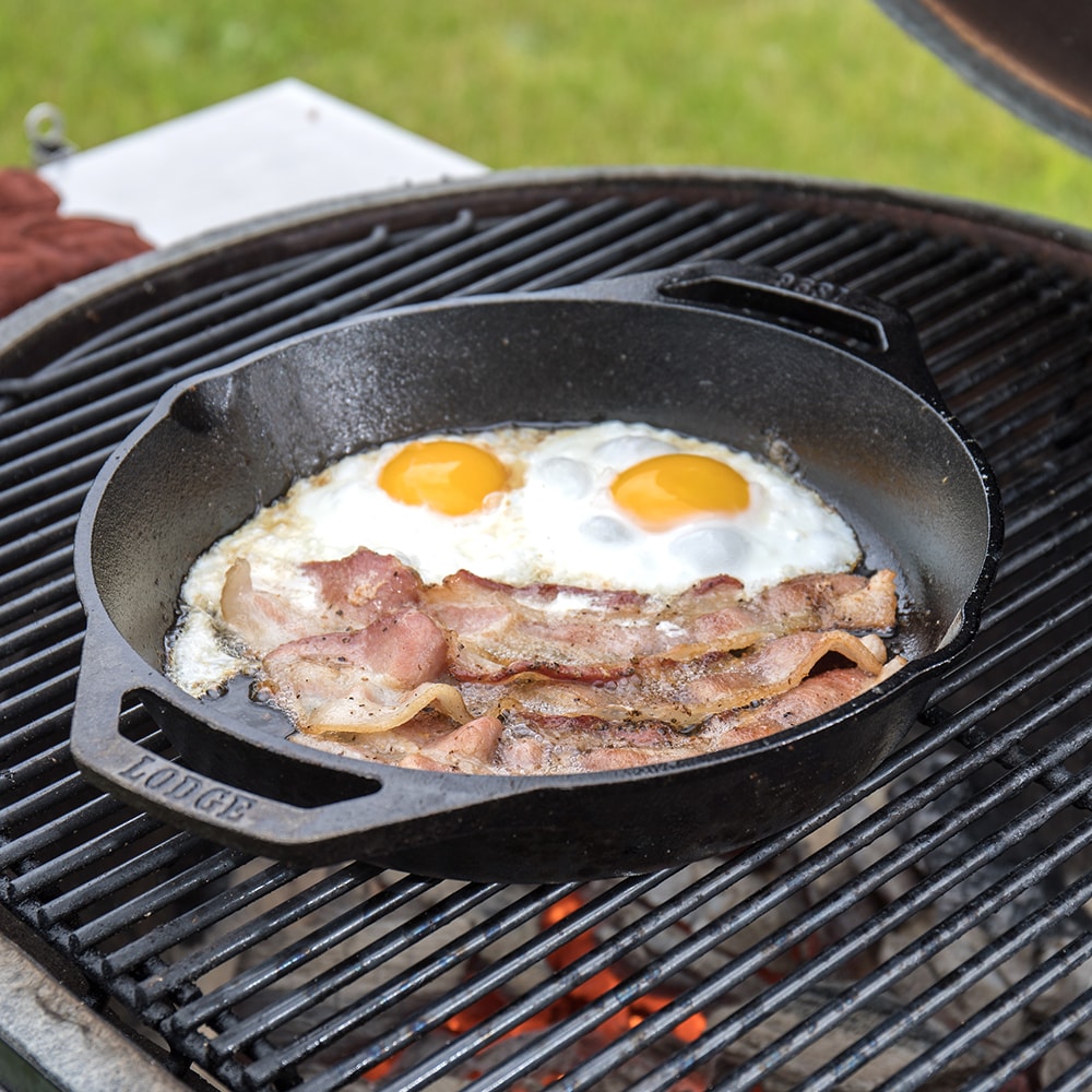 Cast iron round pan with two fried eggs and bacon cooking on outdoor grill in kitchenware under $50 collection