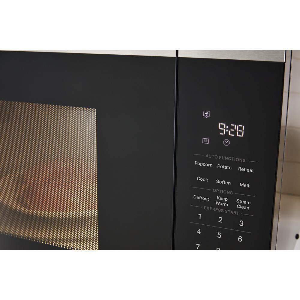 Close-up of black sensor microwave control panel with digital clock and labeled auto functions for cooking and reheating.