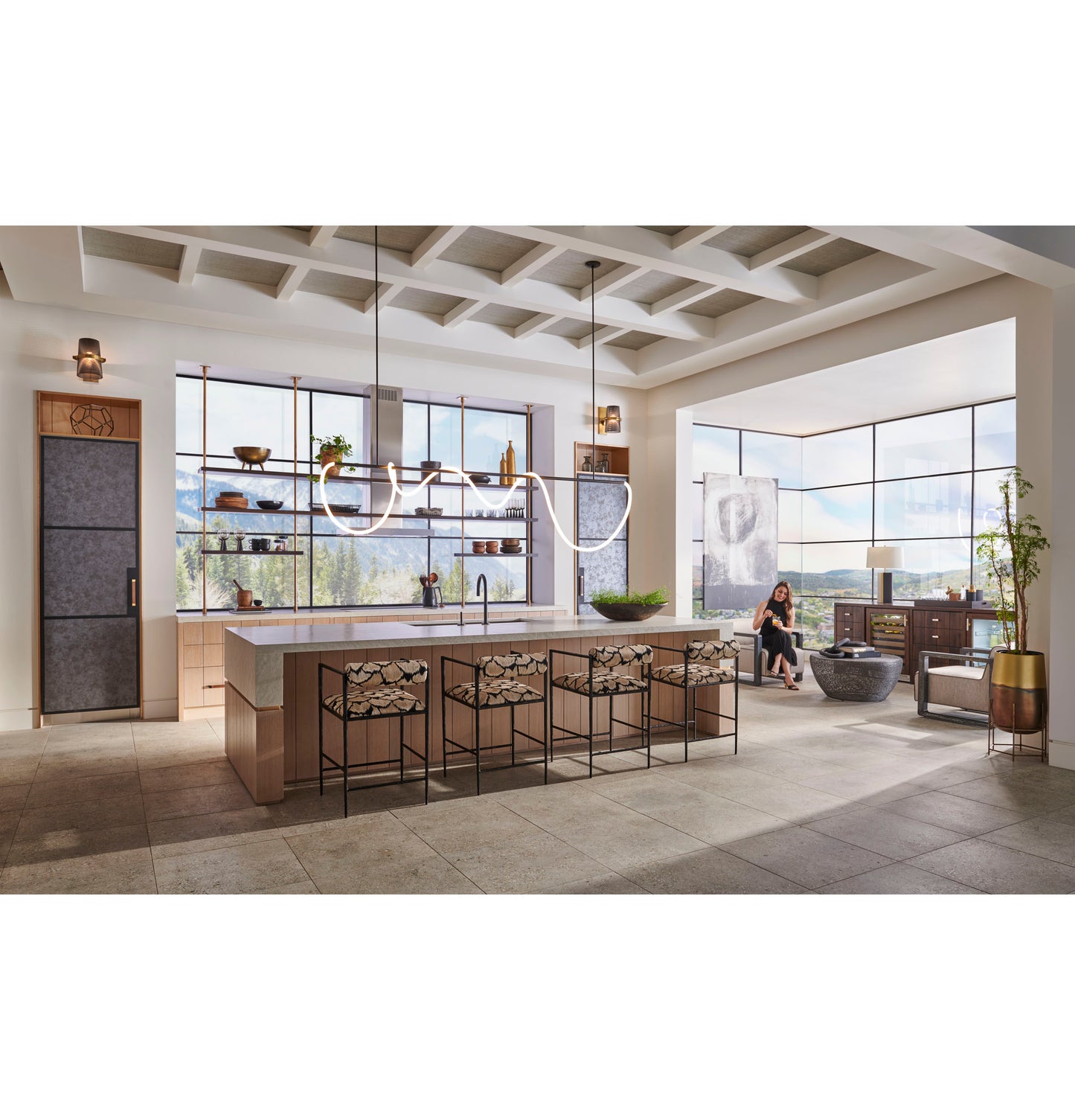 Bright open kitchen with large island, modern minimalist ovens, stone flooring, and scenic window views in appliances setting