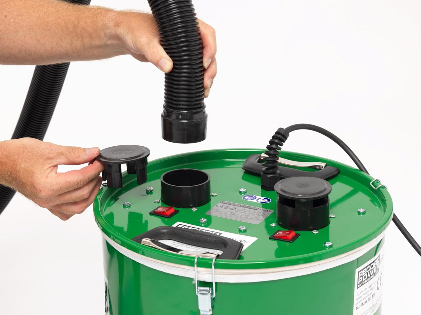 Hands attaching black corrugated hose to green cyclonic dust extractor for tools and home improvement use