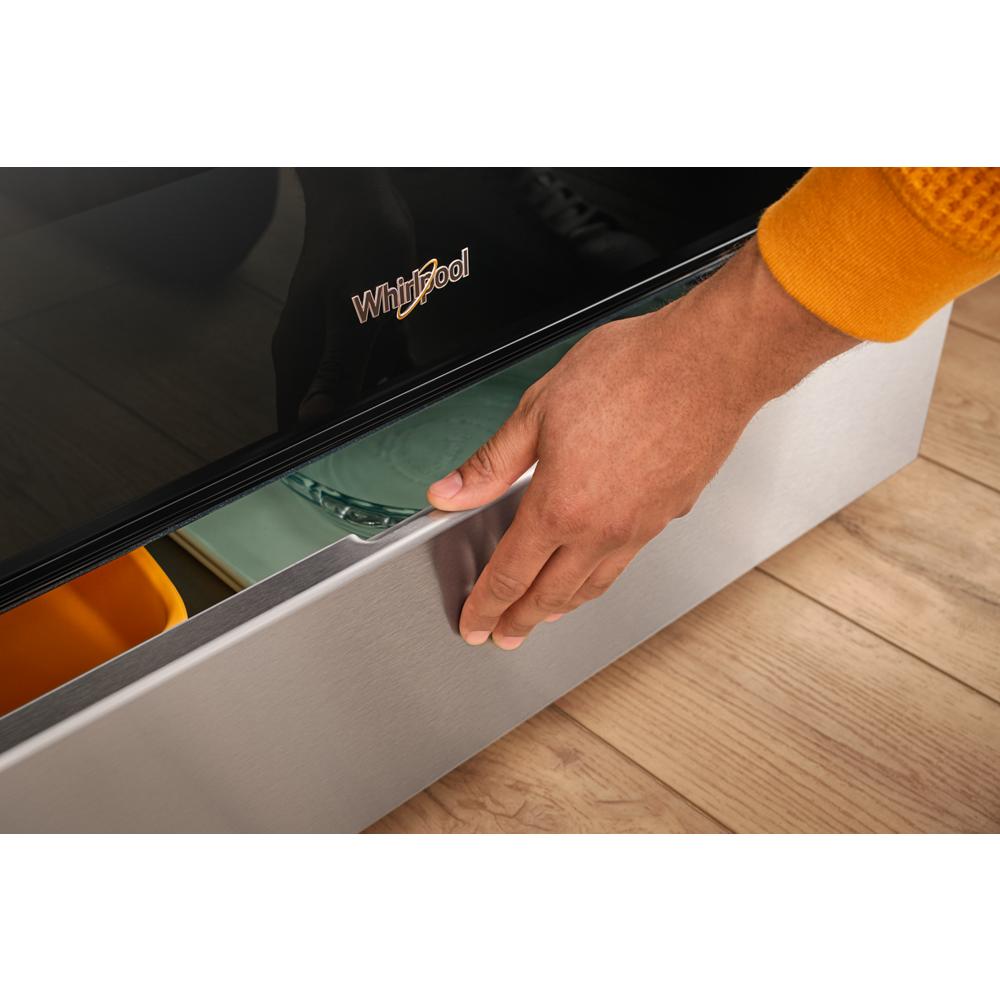 Hand opening the stainless steel storage drawer of a Whirlpool 30-inch induction range on hardwood floor