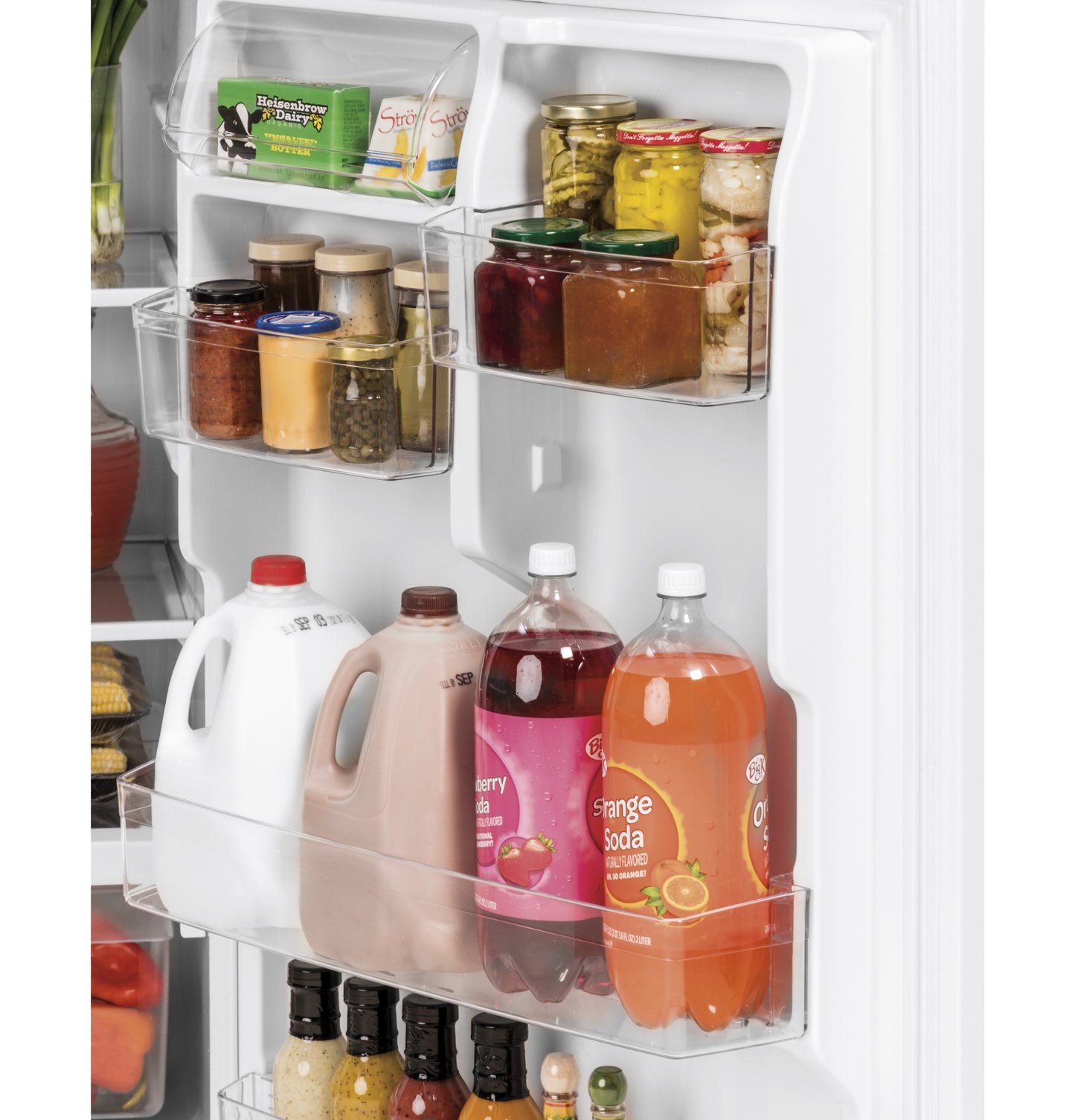 Open refrigerator door showing organized door shelves with condiments, bottled drinks, dairy, and sauces in white fridge interior