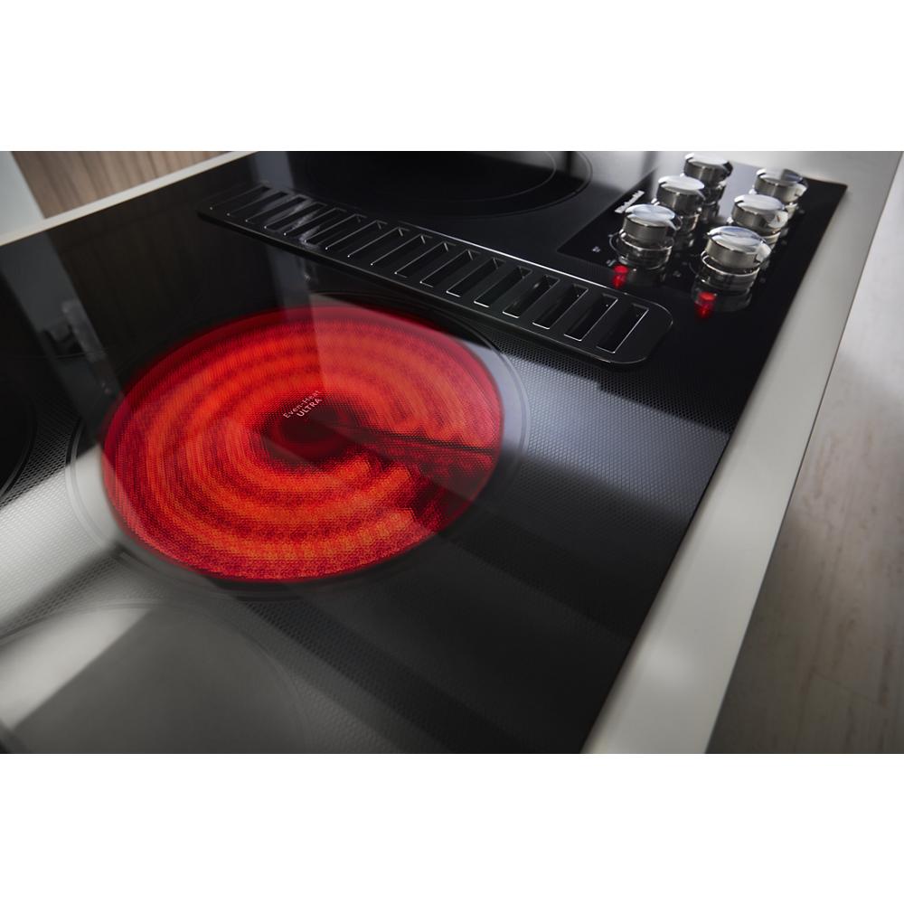 Black electric cooktop with glowing red heating element and stainless steel control knobs from kitchen appliances collection
