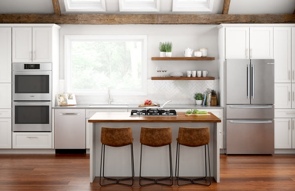 Bright modern kitchen with stainless steel double ovens, gas cooktop island, white cabinetry, and hardwood floors