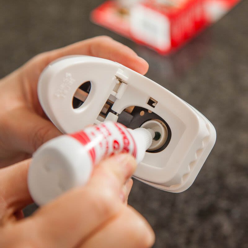 Close-up of hands applying bait to the interior of a white plastic mouse trap for insect and pest control under $50 collection