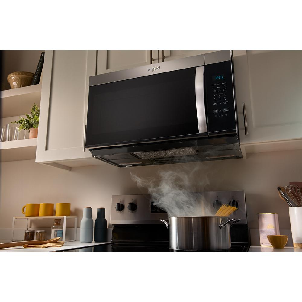 Whirlpool stainless steel over-the-range microwave installed above stove in modern kitchen with pot steaming below