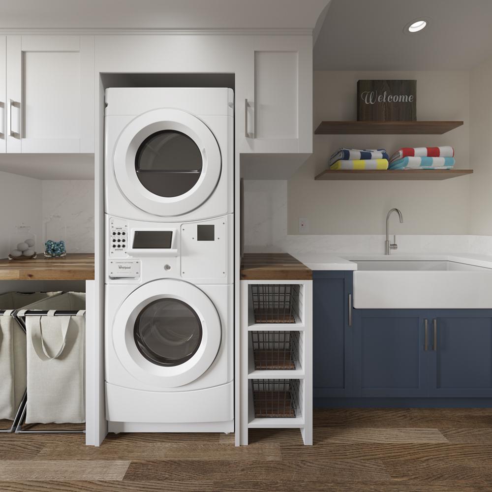 Stacked white front load washer and dryer unit in a modern laundry room with blue cabinets and open wooden shelving