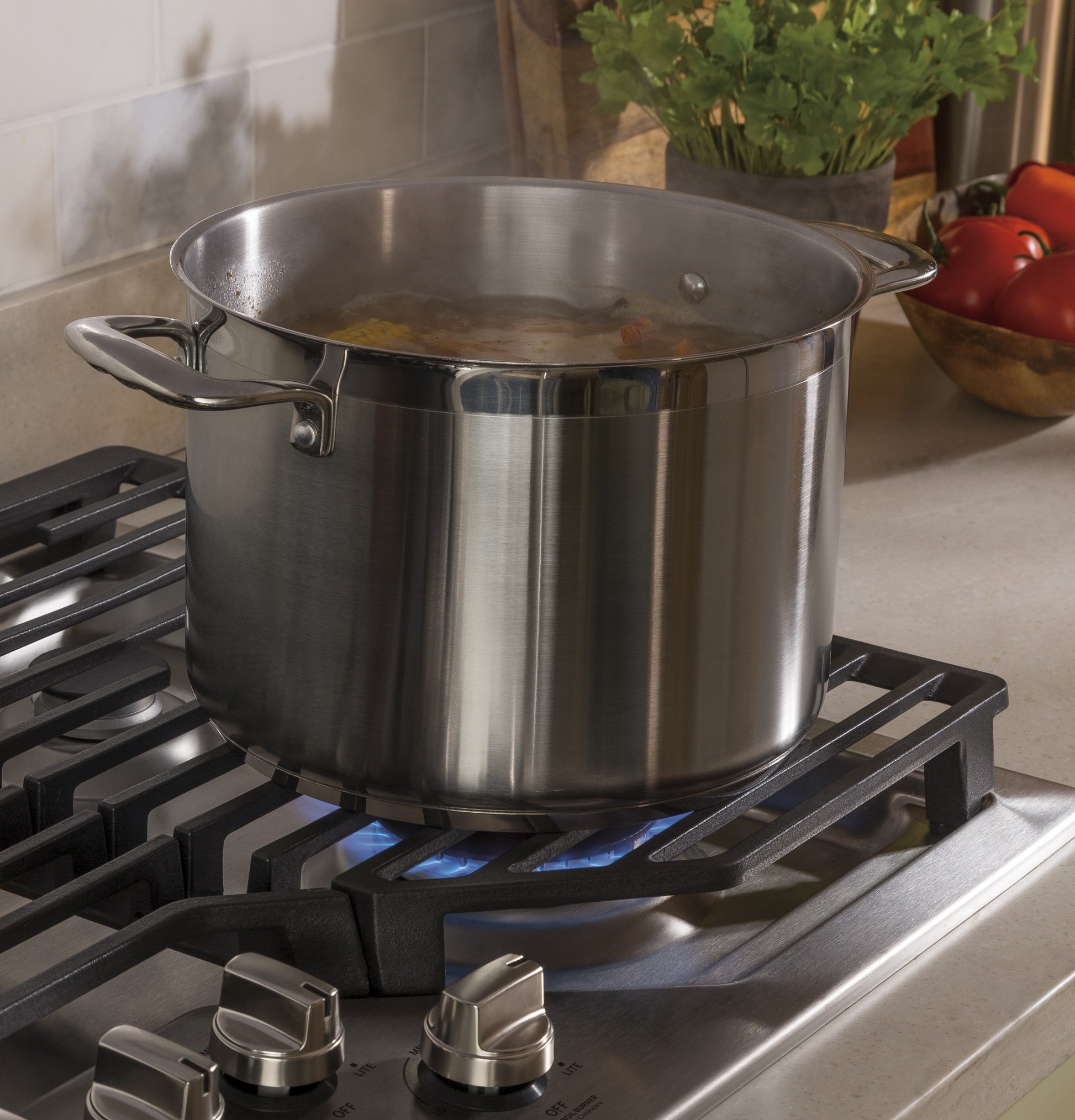 Stainless steel pot simmering on a burner of a built-in gas cooktop in a modern kitchen setting