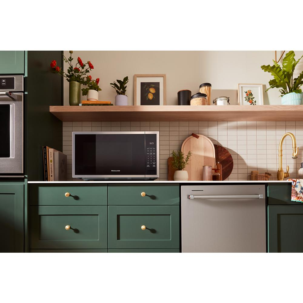 Stainless steel microwave with digital keypad on countertop in kitchen with green cabinets and wood shelf in Microwaves collection