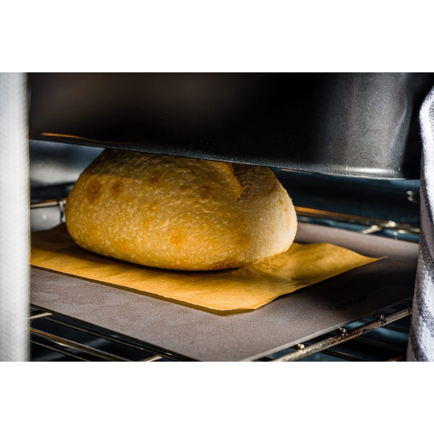 Loaf of bread baking on parchment paper inside an oven for Kitchenware and Bakeware collections under $100