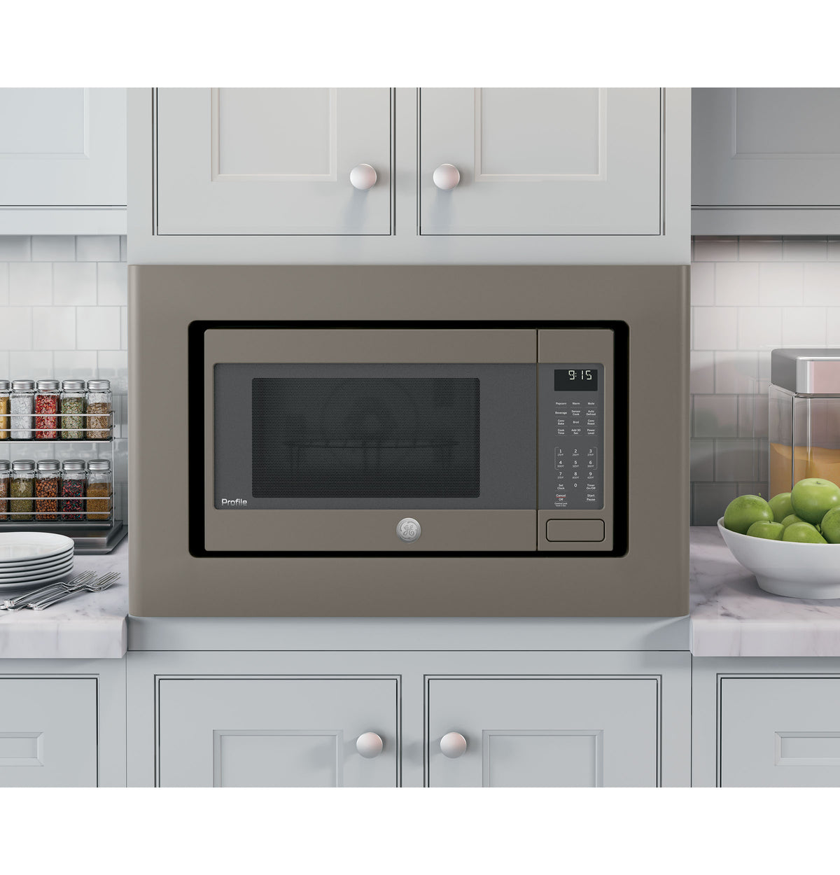 Built-in microwave framed by matte trim kit installed in gray kitchen cabinetry with countertop and backsplash