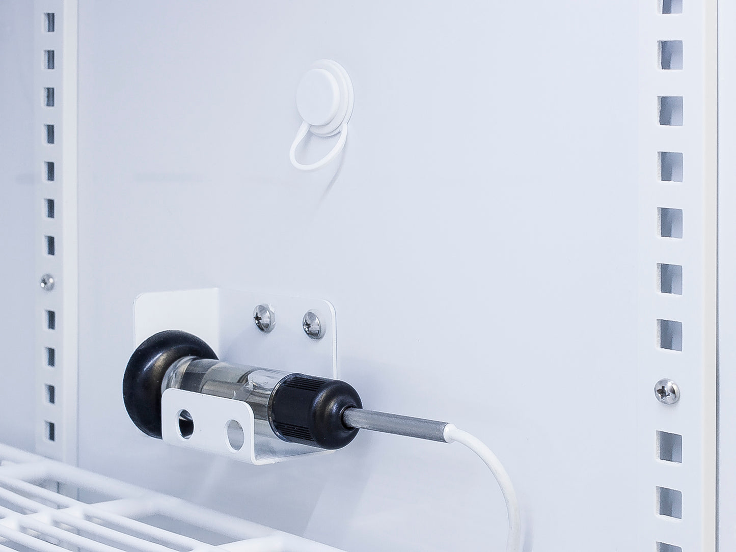 Temperature sensor probe attached inside white upright freezer with wire shelving from freezer collection