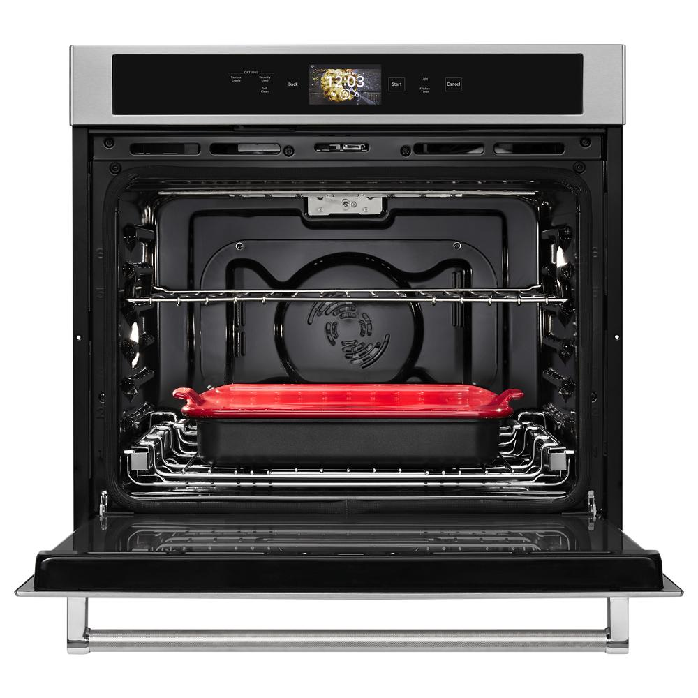 Open stainless steel wall oven with digital touchscreen and red baking dish inside, part of KitchenAid appliances collection