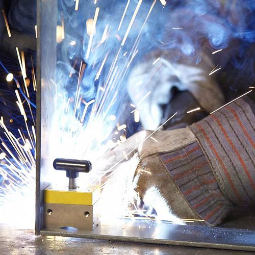 Close-up of a metalworking clamp in use with bright sparks flying during welding for home improvement projects