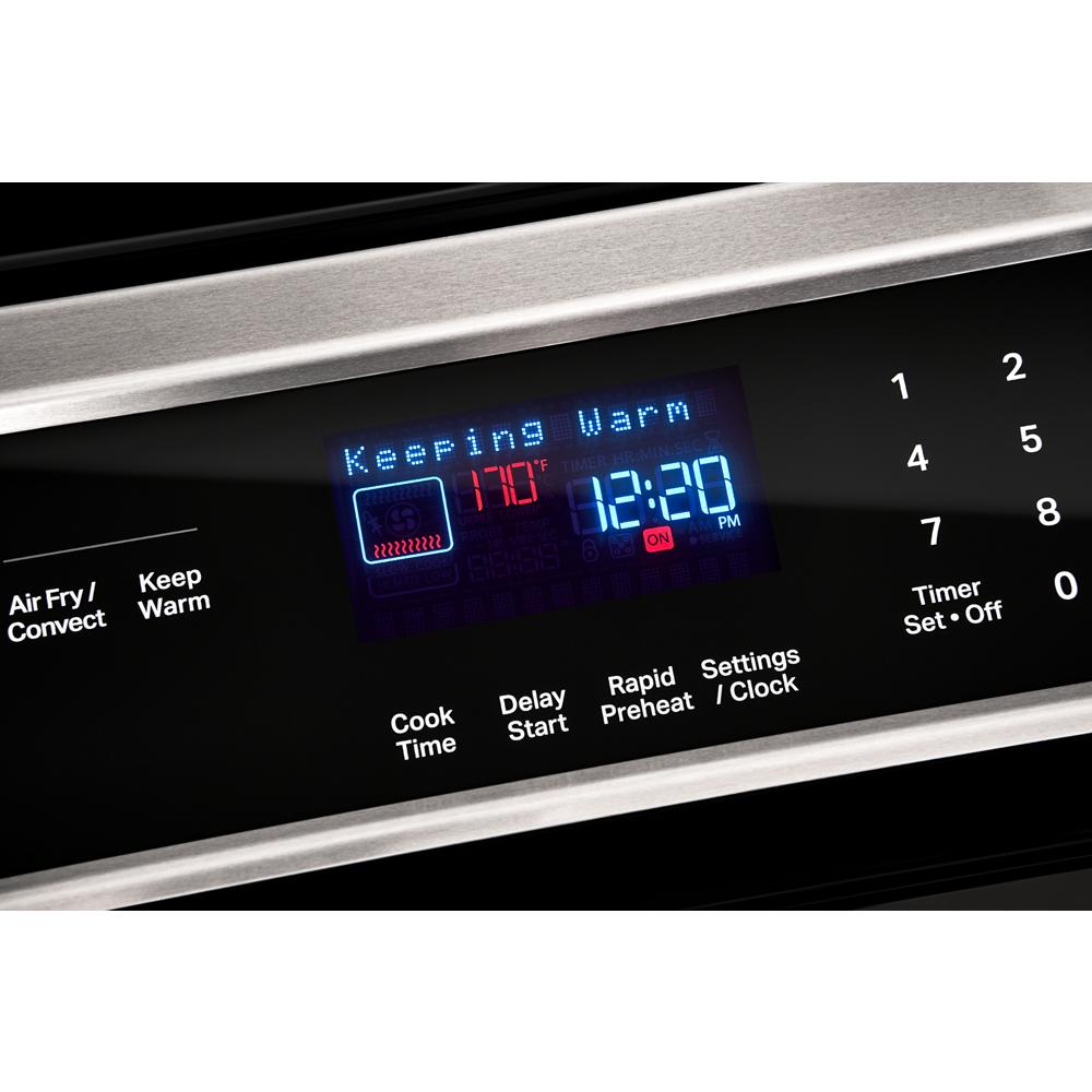 Close-up of digital control panel on black induction range showing keeping warm mode and timer settings