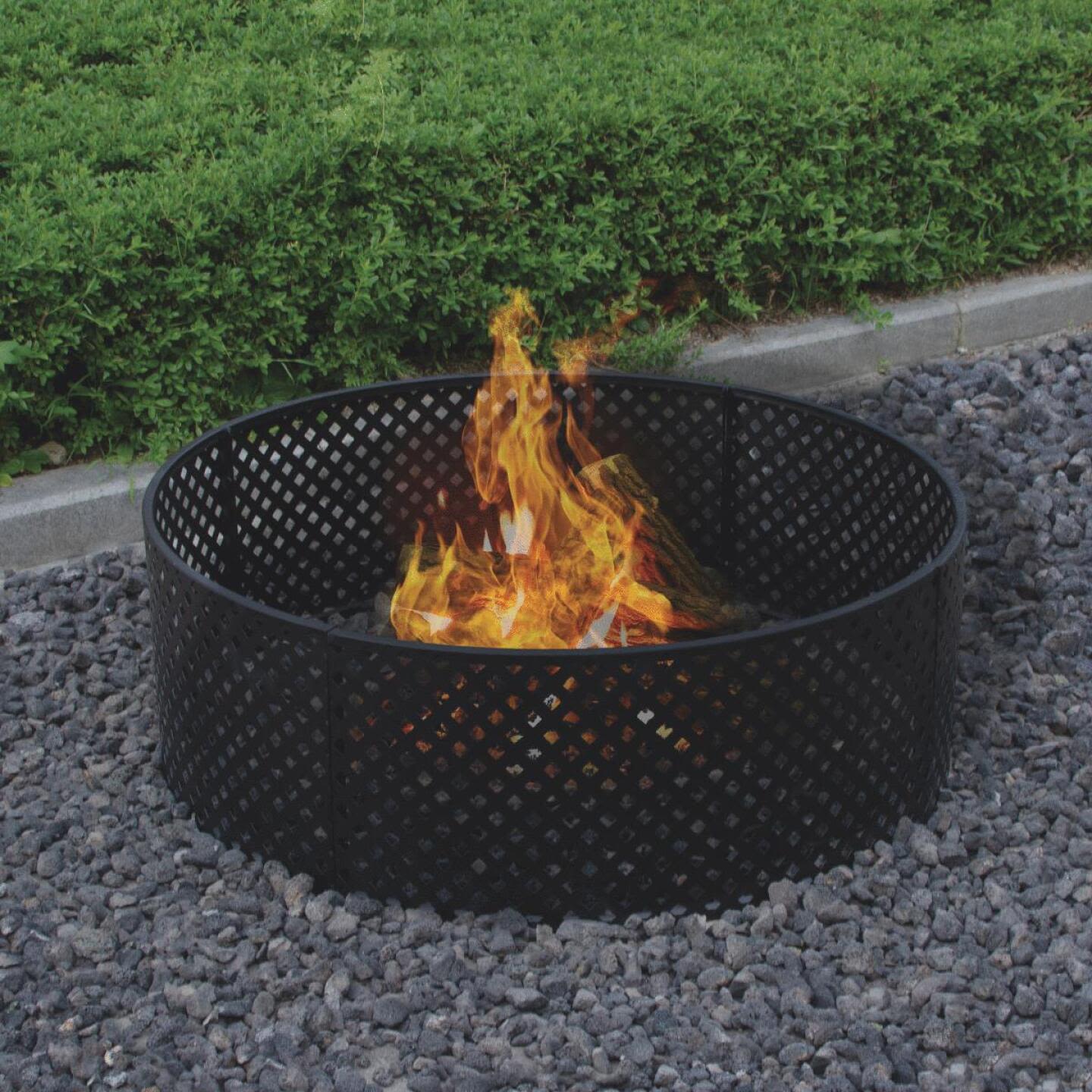 Black powder coated steel fire ring with lattice design surrounded by gravel in outdoor living and patio furniture setting