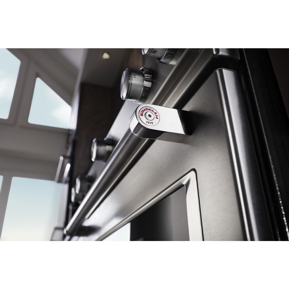 close-up of stainless steel gas range door handle with KitchenAid logo and control knobs on slide-in cooking appliance