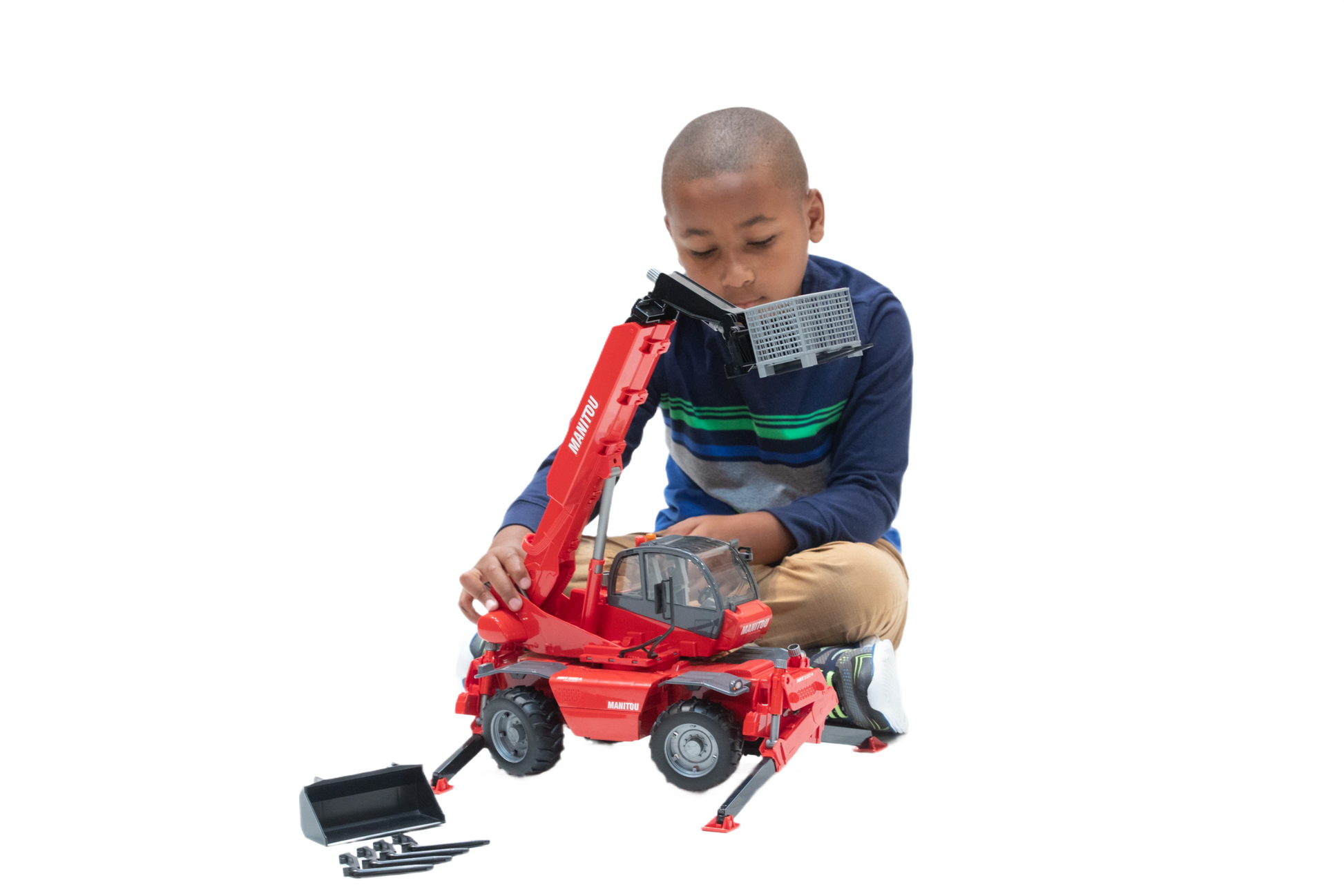 Boy playing with red Bruder Manitou telehandler toy featuring extendable arm and bucket attachment for construction play