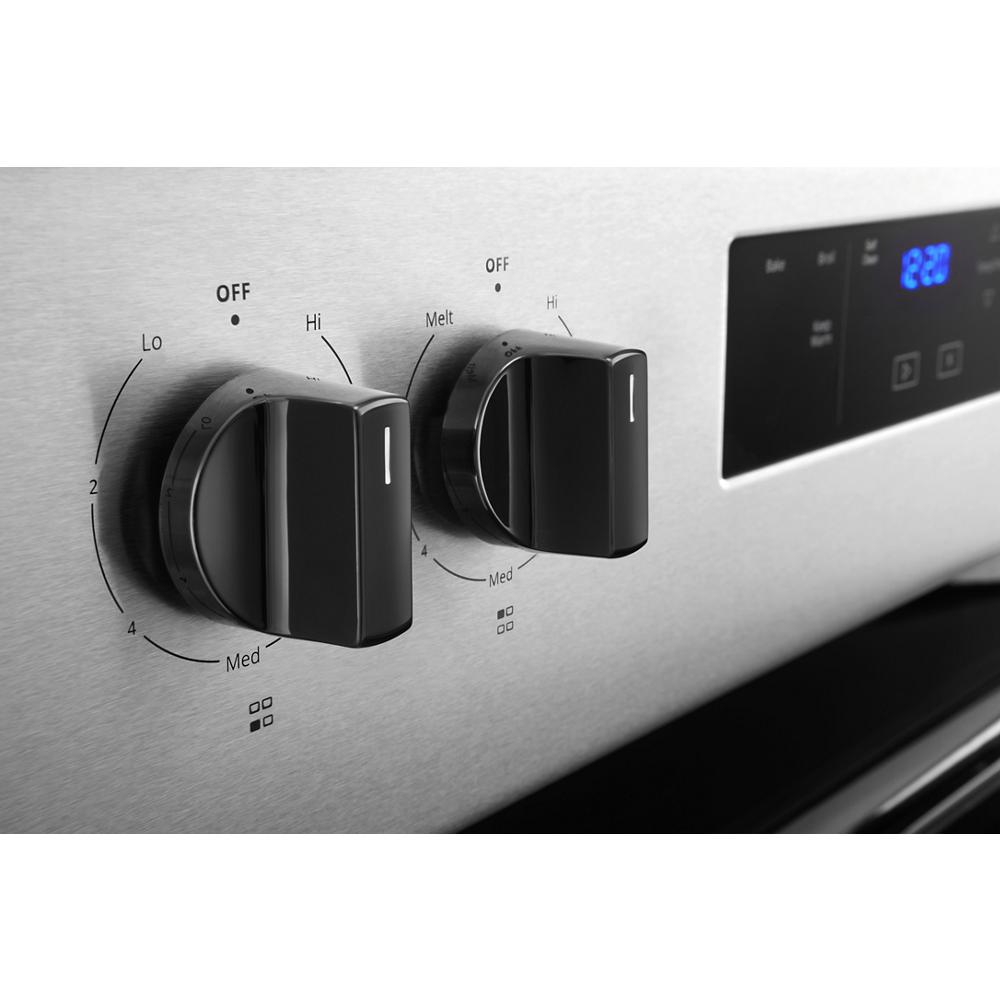 close-up of stainless steel electric range control knobs with temperature settings and digital timer display