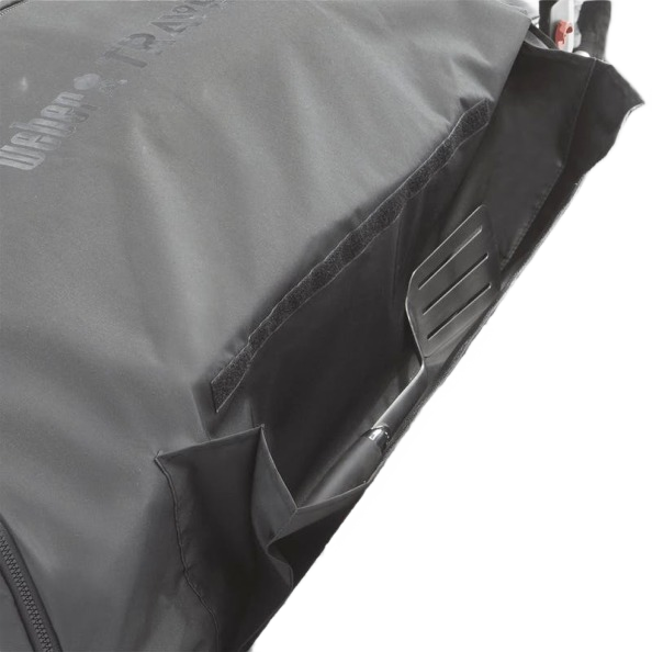 Close-up of a black fabric cargo protector with storage pocket holding a metal grilling spatula for home improvement use