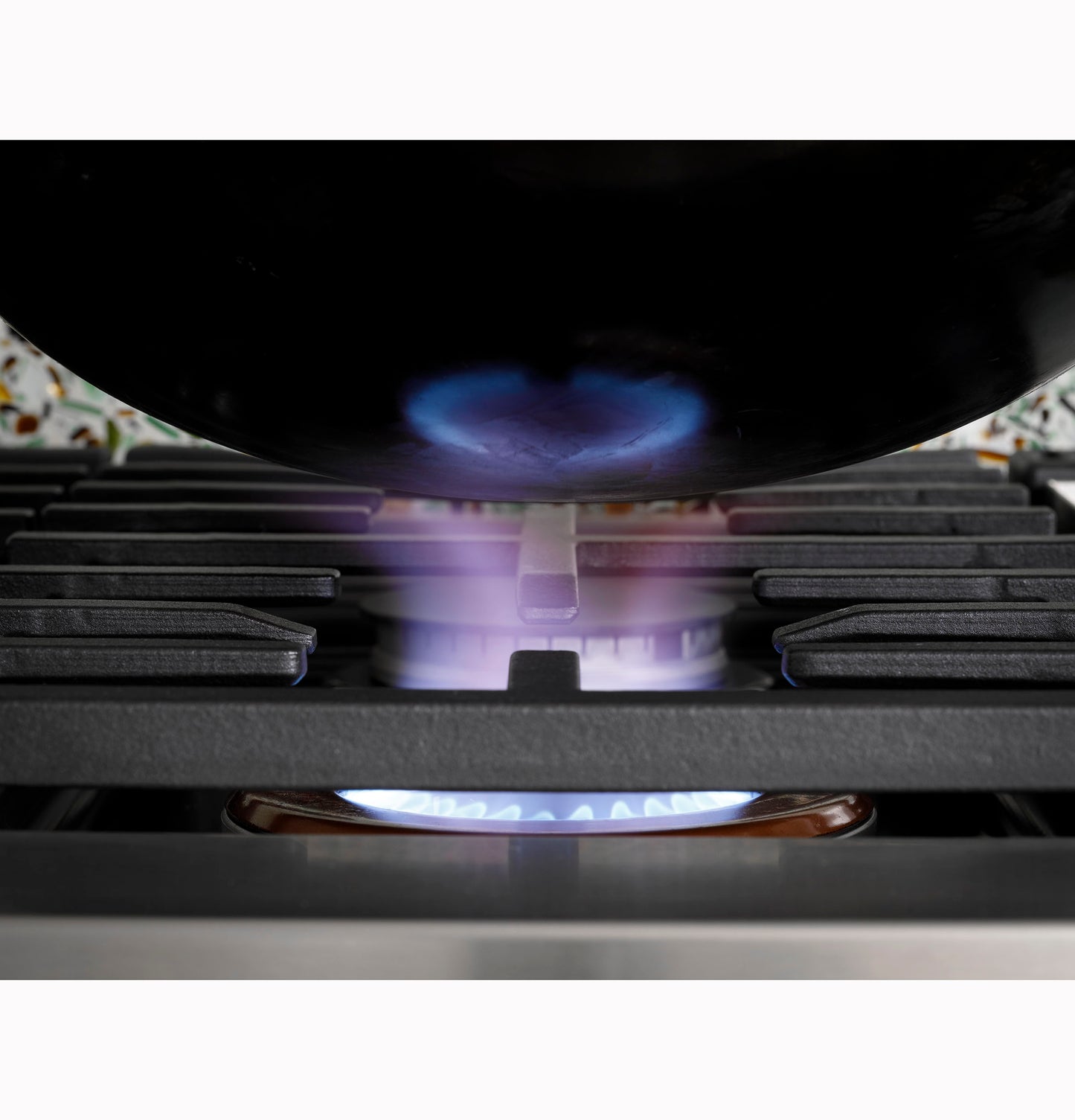 Close-up of natural gas flame under cookware on black cast iron grate of commercial-style rangetop in kitchenware collection