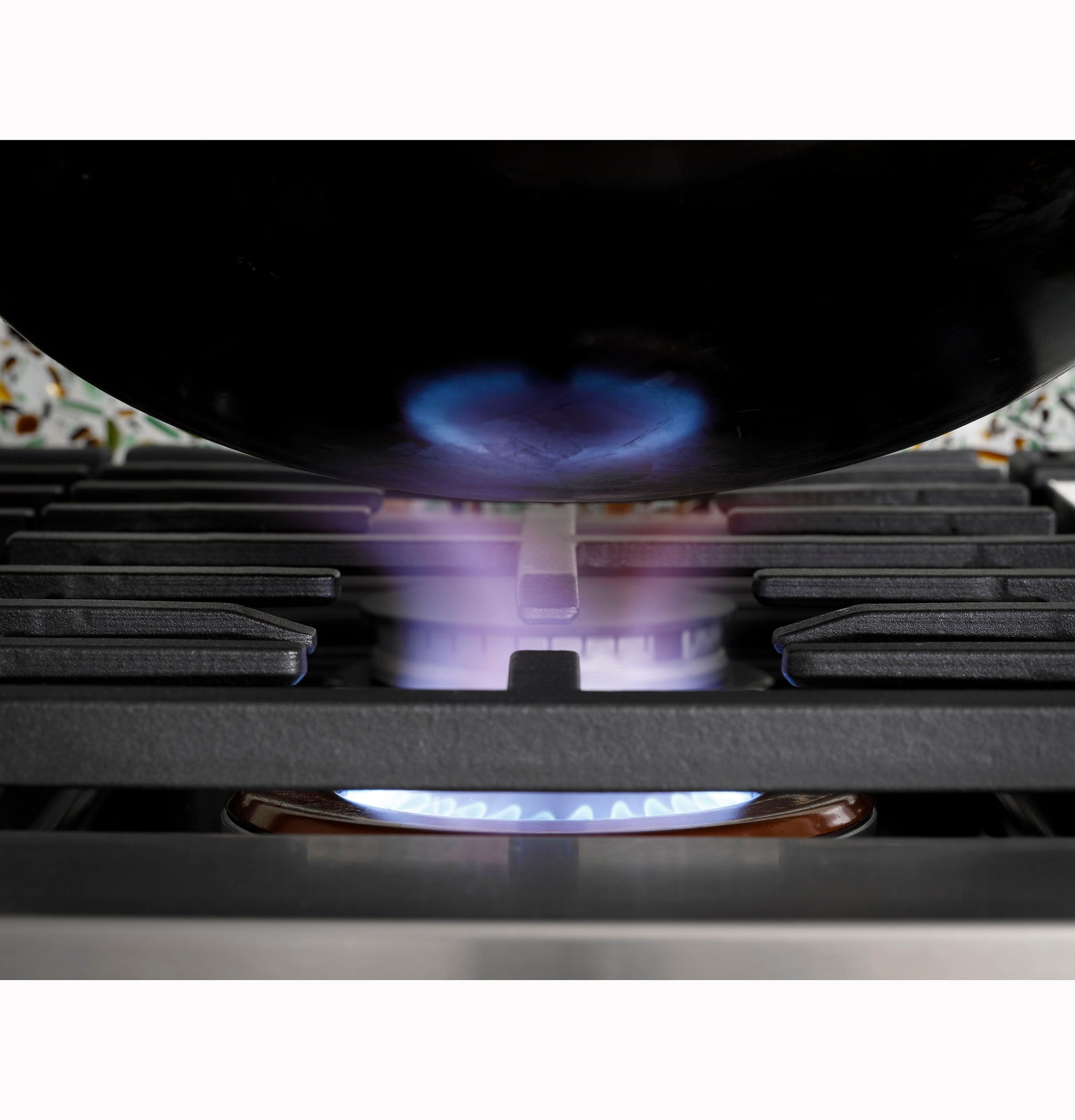 Close-up of natural gas flame under cookware on black cast iron grate of commercial-style rangetop in kitchenware collection