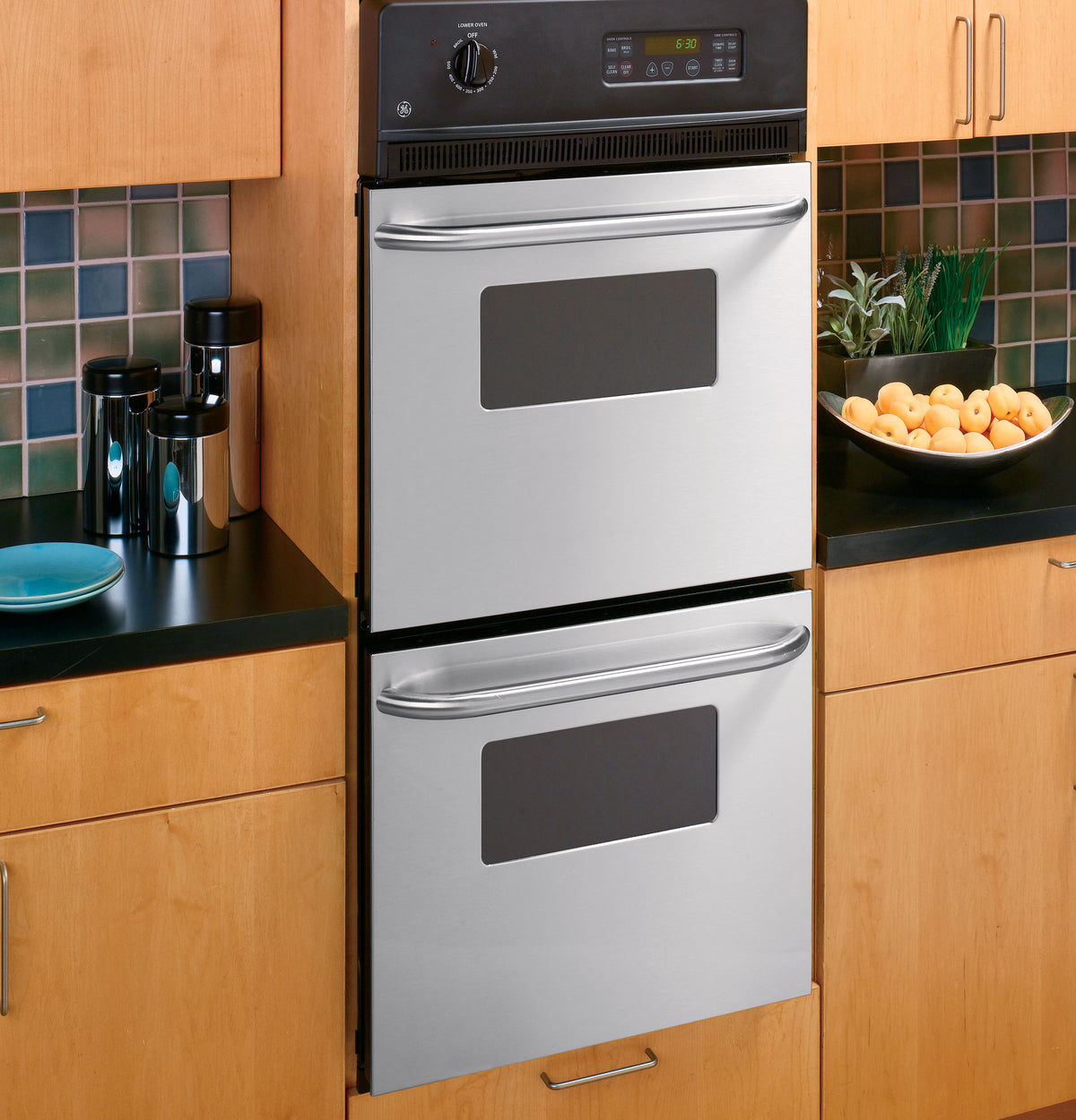 Built-in stainless steel double wall oven with digital controls integrated into light wood kitchen cabinetry in Appliances collection