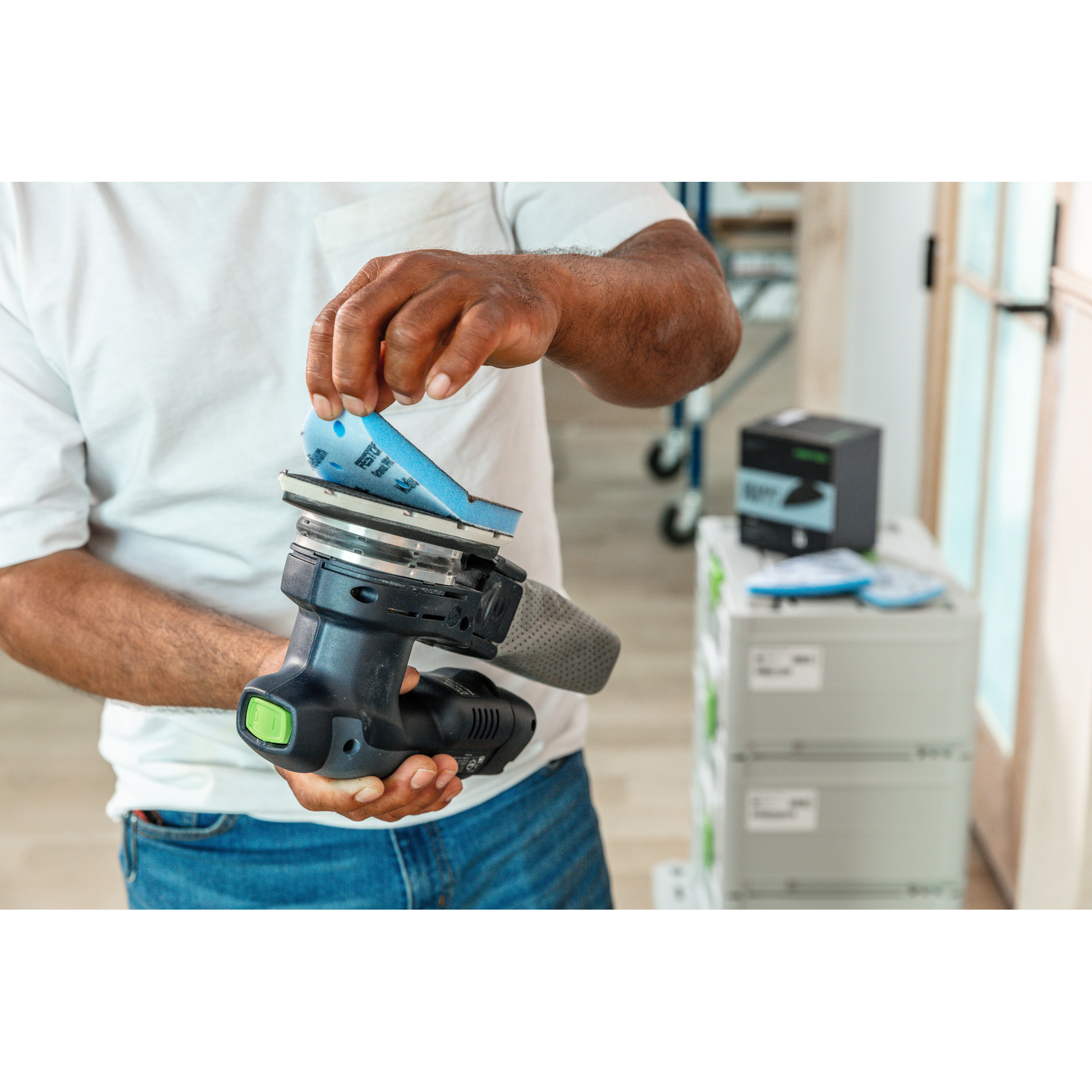 Person attaching blue Festool abrasive sheet to power sander, part of woodworking and tool accessories collections under $50