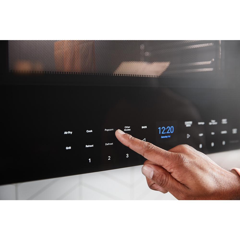 Close-up of hand selecting cooking mode on touchscreen control panel of black built-in over-the-range microwave