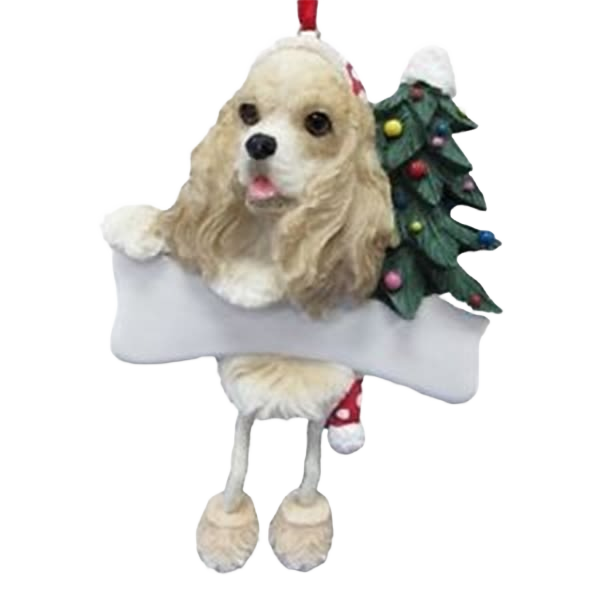 Cocker Spaniel dog ornament with dangling legs holding a white bone and decorated Christmas tree behind