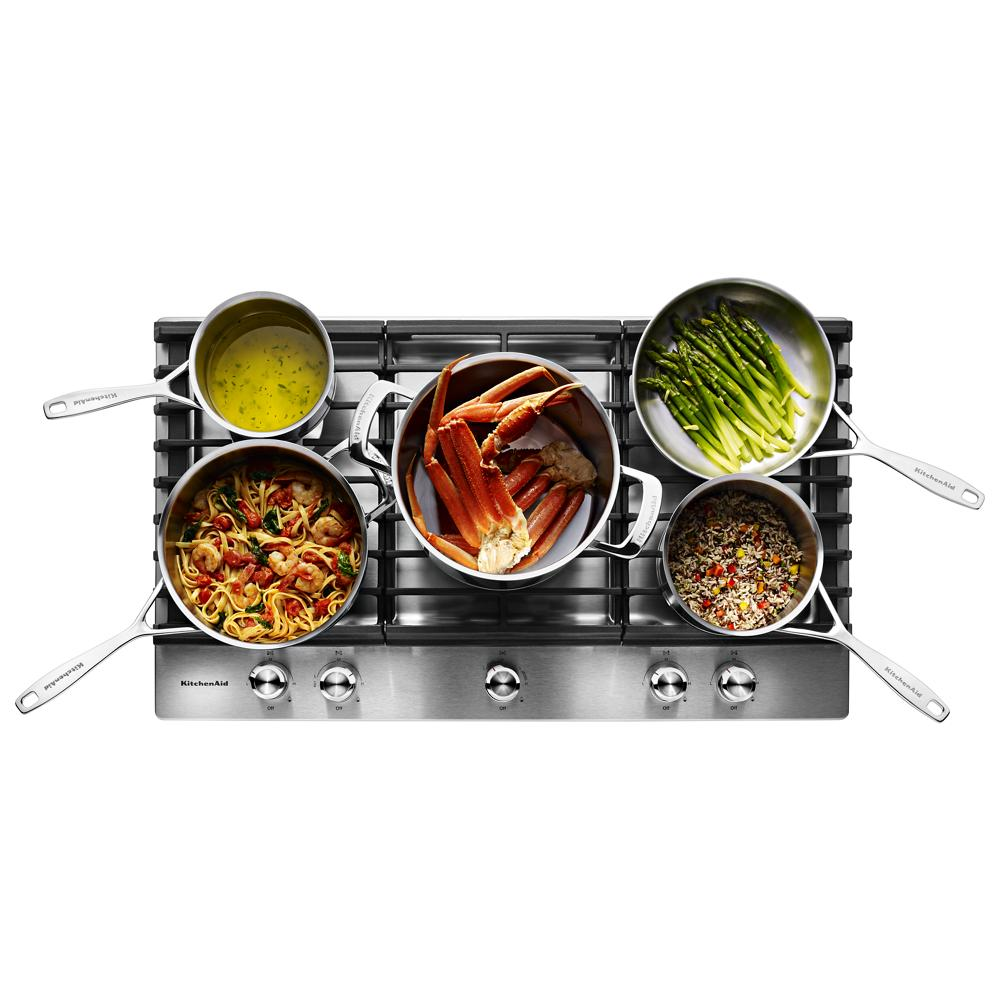 Overhead view of a stainless steel 36-inch 5-burner gas cooktop with pots cooking seafood, vegetables, and grains in KitchenAid collection