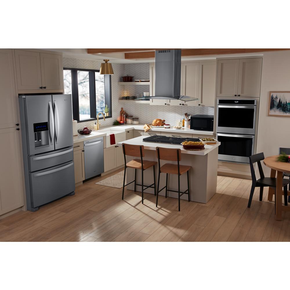 Modern kitchen featuring a stainless steel island mount range hood, double wall ovens, refrigerator, dishwasher, and wood flooring