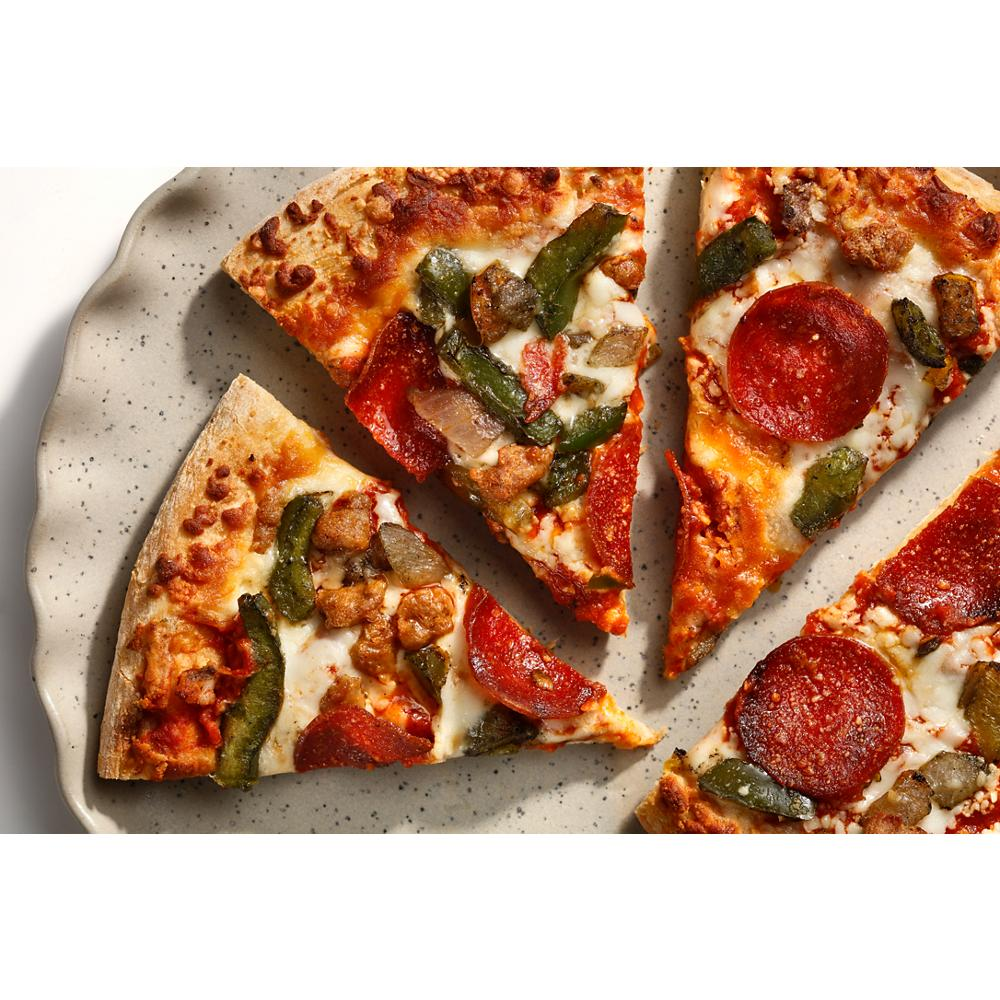 Close-up of sliced pepperoni and vegetable pizza on speckled ceramic plate in kitchenware setting