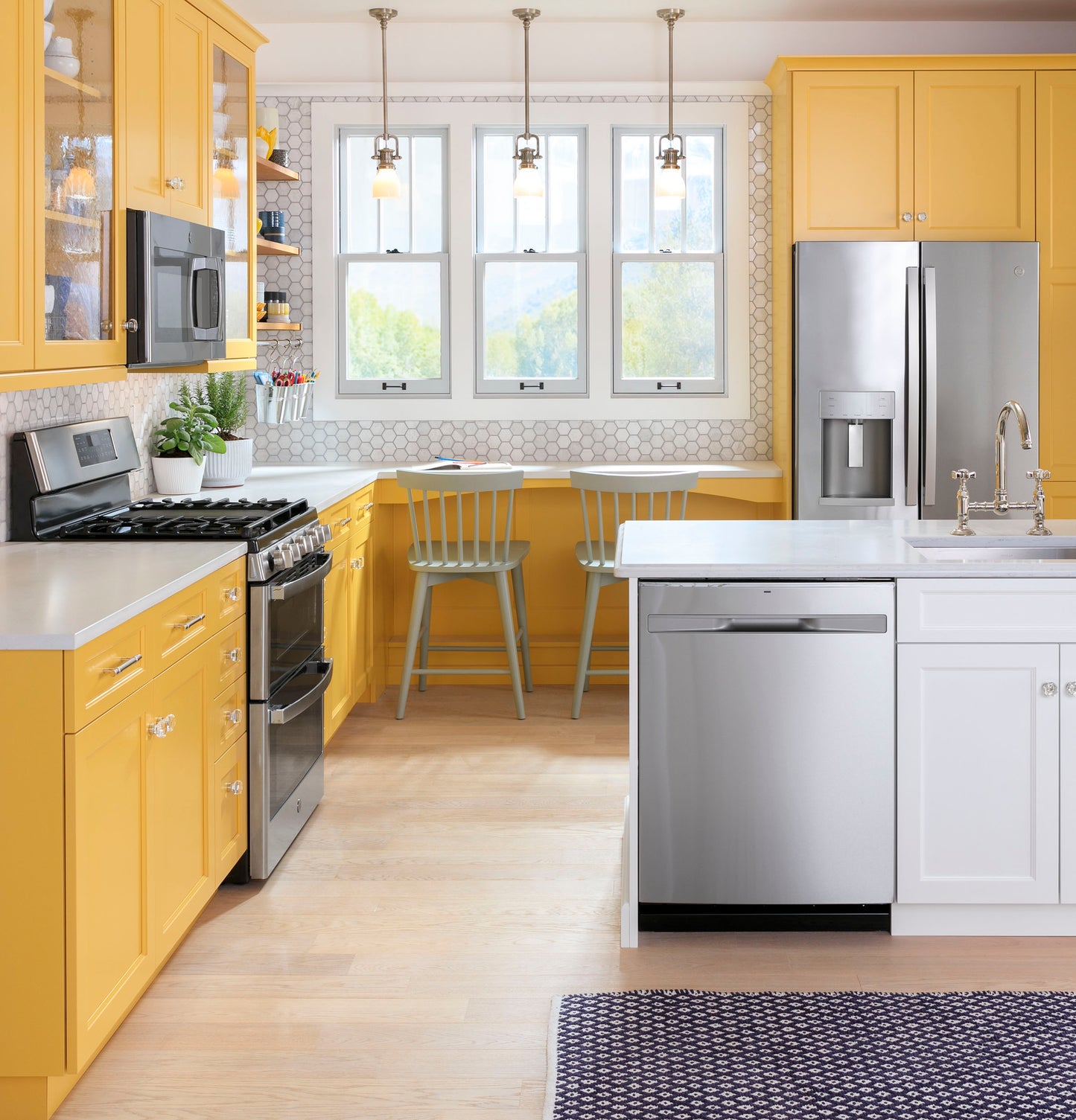 Bright kitchen with yellow cabinetry featuring a fingerprint resistant over-the-range microwave and stainless steel appliances collection.