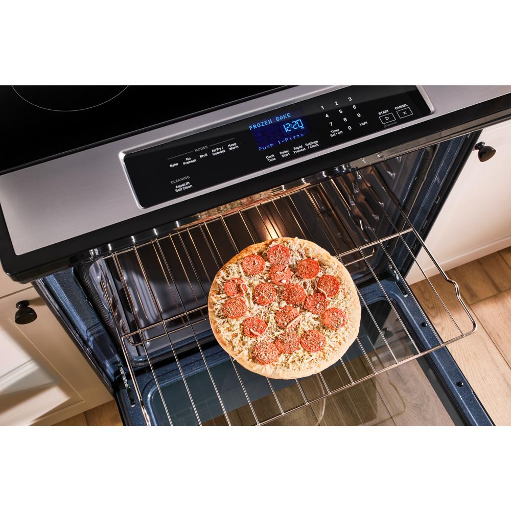 Open oven in modern kitchen with frozen pizza baking on middle rack and digital control panel above door