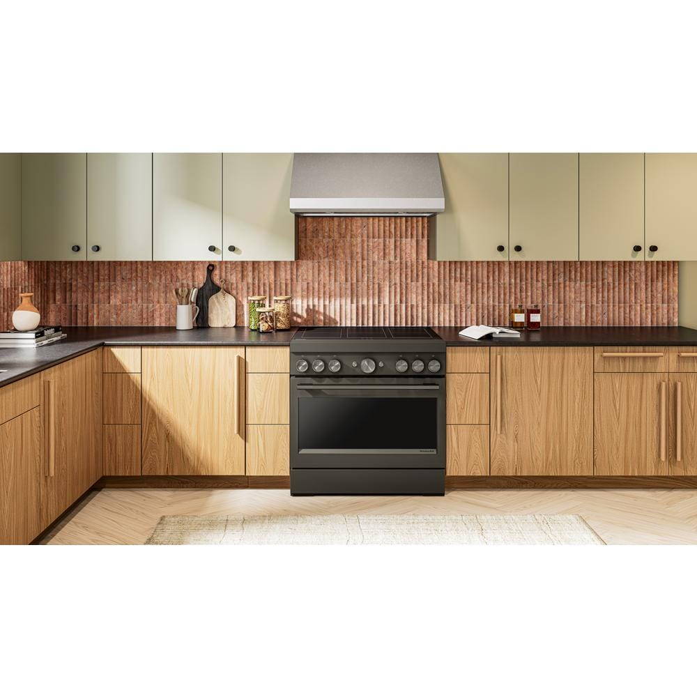Modern kitchen with 36-inch dark freestanding induction range surrounded by light wood cabinets and textured backsplash